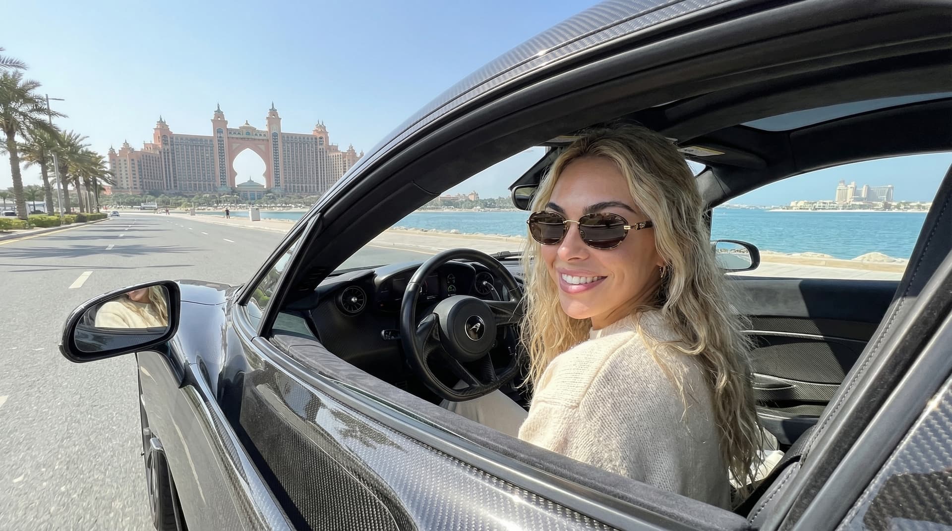 Aerial view of Palm Jumeirah, world's largest man-made island, showing dramatic palm-frond design, luxury hotels, sparkling blue waters, palm-frond villas, and 78km of added coastline from high-altitude drone photography