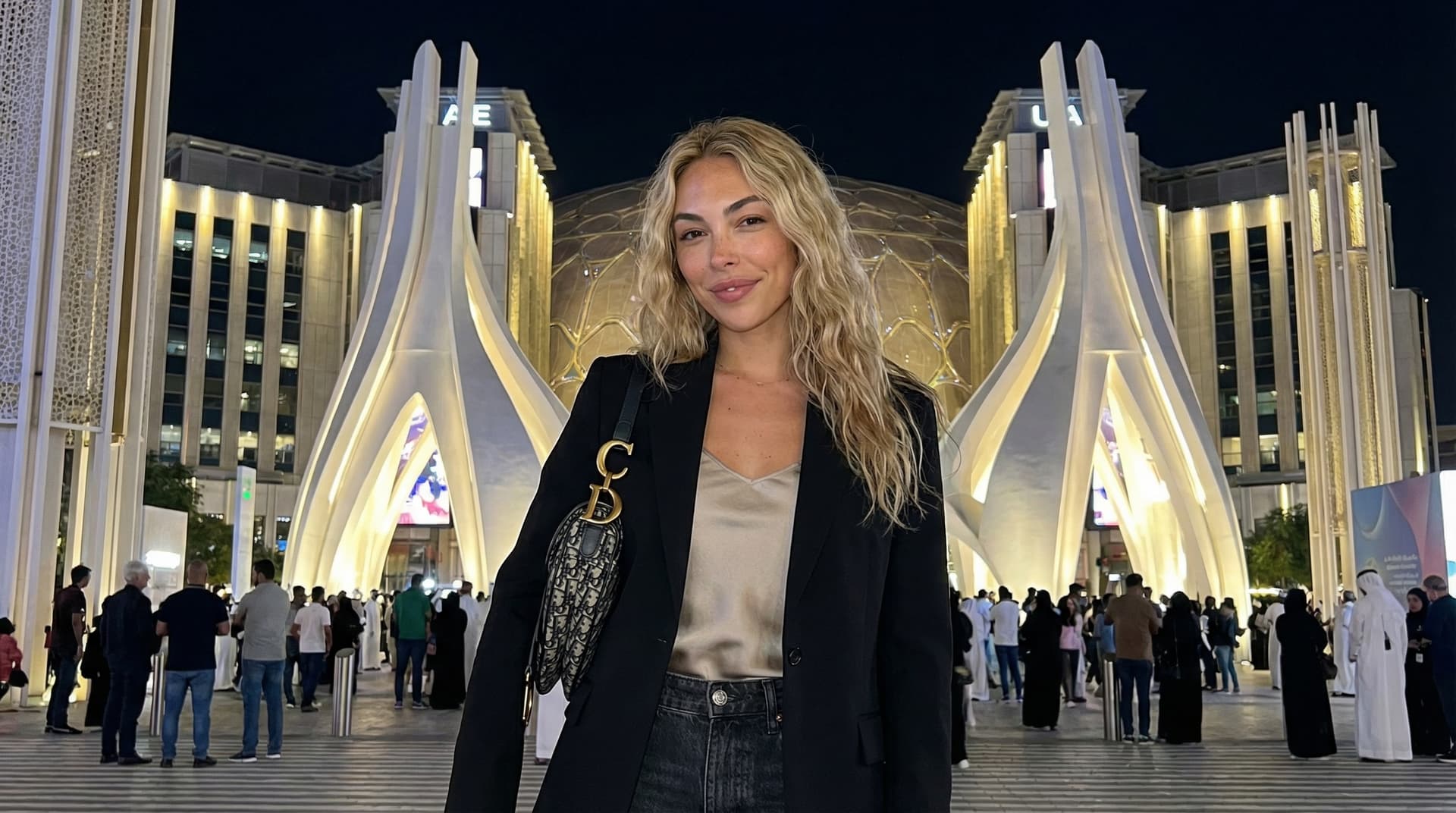 UAE Pavilion at Dubai Expo illuminated at night with dynamic LED lighting, falcon-inspired architecture designed by Santiago Calatrava, intricate oculus details, and futuristic silhouette against Dubai city skyline