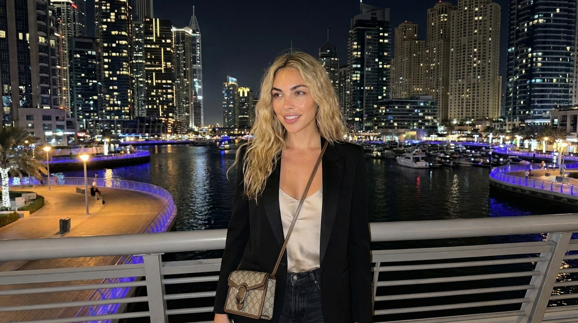 Dubai Marina towers at night with glittering lights reflected in water, illuminated boats, vibrant nightlife, long-exposure city lights, and over 200 residential towers creating stunning waterfront skyline